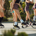 Beautiful women in sportswear jumping in a kangoo jumps shoes at the street on summer's sunny day